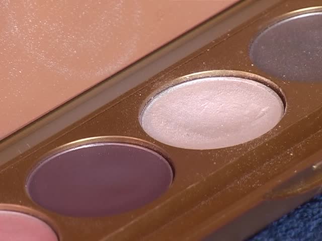 Eye shadow  and cosmetics in an open container with a mirror in the background