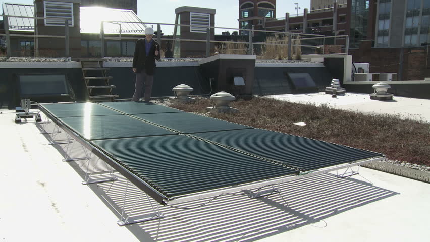 Technician inspects a solar power installation on a roof top. This could also be a building contractor, workman, architect or site inspector.