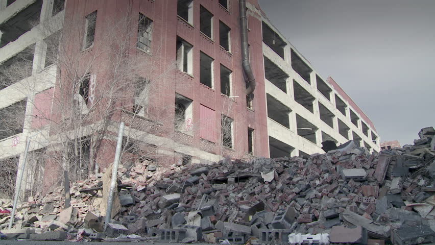 Developer (could be an architect, investor, contractor or other business person) walks into shot and looks around at the collapsed buildings around him, making notes. Low, wide angle shot.