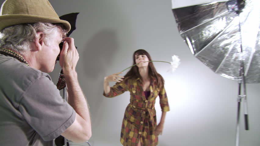 Photographer takes pictures of girl with giant flower. Deliberately edgy, hand-held camera in studio.