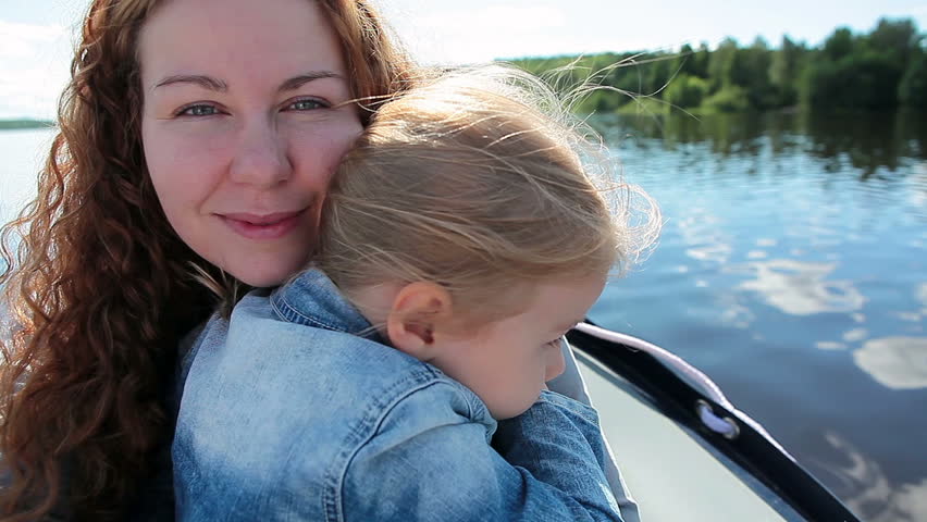 Mother and her small daughter driving on motorboat bow on the lake, Close-up