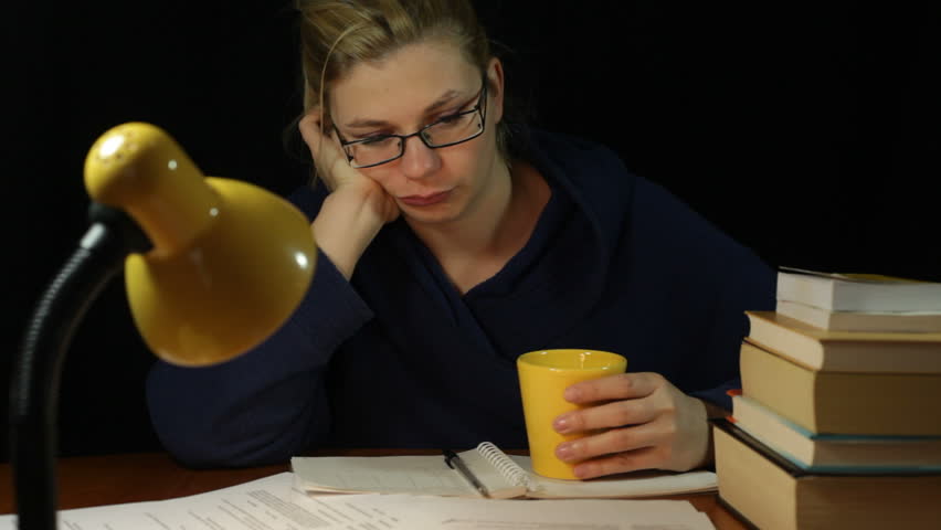 Unhappy tired overworked woman in bathrobe drinking coffee in home office at night