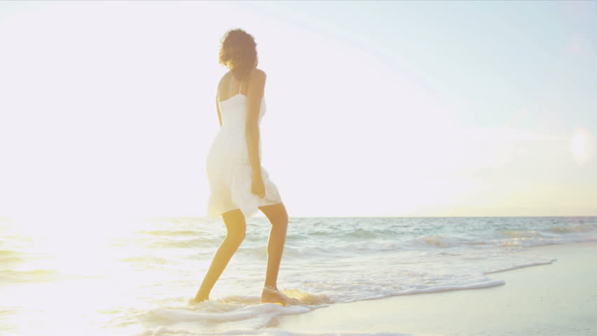 Pretty girl in sundress reveling being alone by ocean at sunrise on beach vacation sun, lens flare shot on RED EPIC