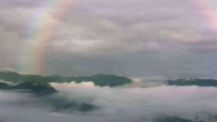 In the mountains after a rain. Rainbow shines. Mist rises from the lowlands