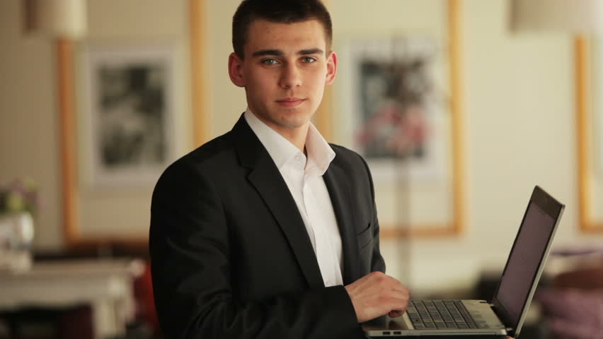 Young adult with laptop looking at camera and laughing
