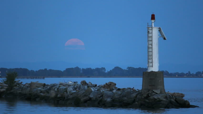 Moonrise Fraser, River, Steveston. A full moon rises over the Fraser River by the entrance to Steveston Harbor. British Columbia, Canada, near Vancouver.