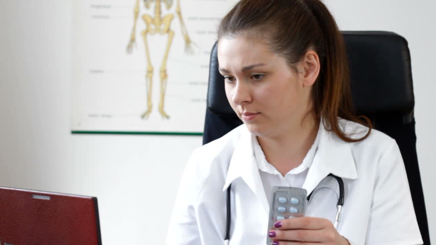 Young female doctor comparing pills on the  internet