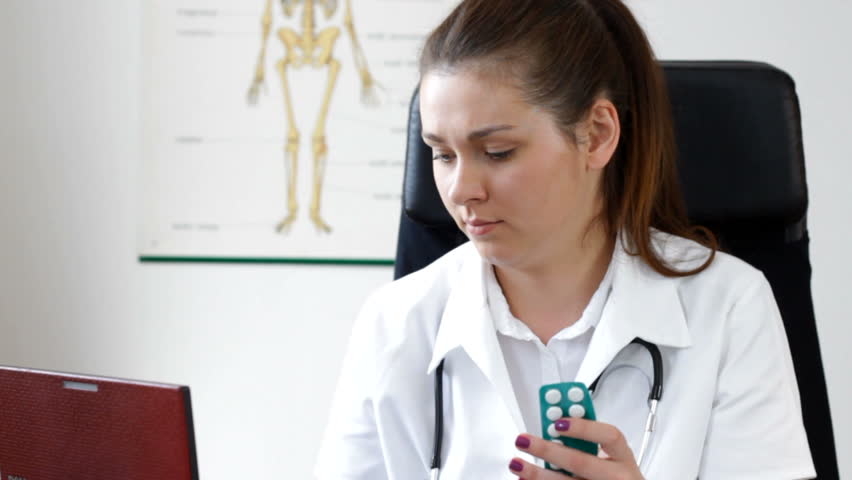 Young female doctor comparing pills on the  internet