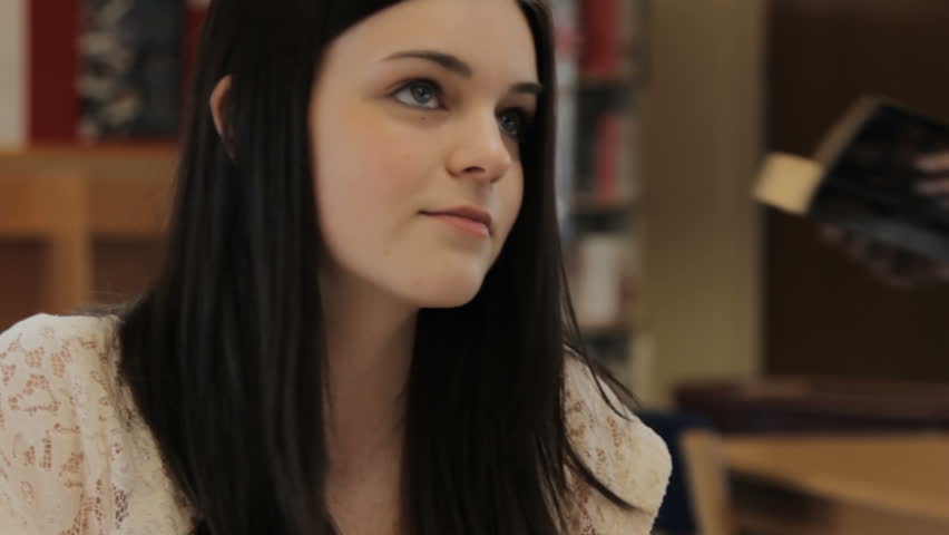 Teenage boy and girl flirting - in school library