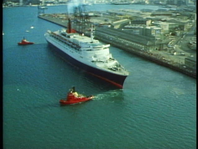 QE2 aerial, tugs pulling ship away from dock, wide shot