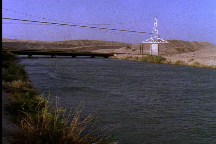 IMPERIAL VALLEY, CALIFORNIA - CIRCA JUNE 1996: Wide shot of water in All American Canal with hydroelectric wires passing over.