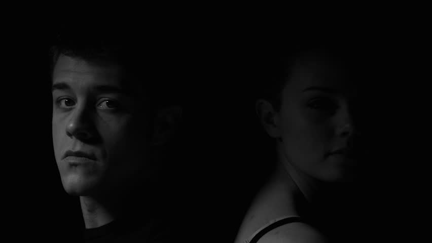Man and woman sitting back to back in black and white. Experimental lighting.