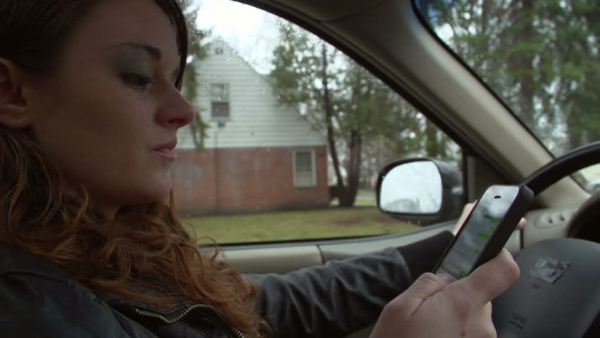 Young woman on her phone and driving