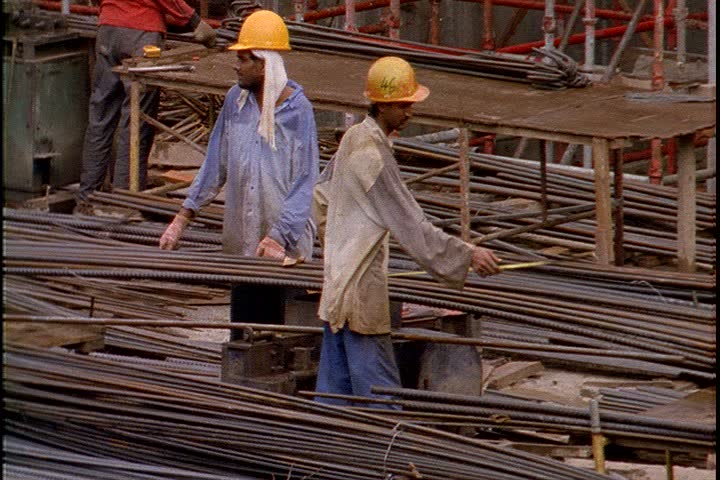 KUALA LUMPUR - OCTOBER 25, 1999: MS workers in hardhats lashing iron rods together. 