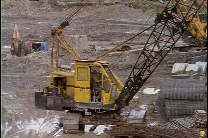 KUALA LUMPUR - OCTOBER 25, 1999: Kuala Lumpur construction site; WS yellow crane in pit, tilt up to crane rigging moving through foreground. 