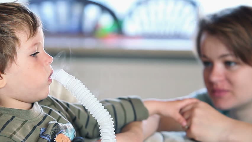 Mother and little boy using nebulizer to inhale medicine, shallow DOF, panning
