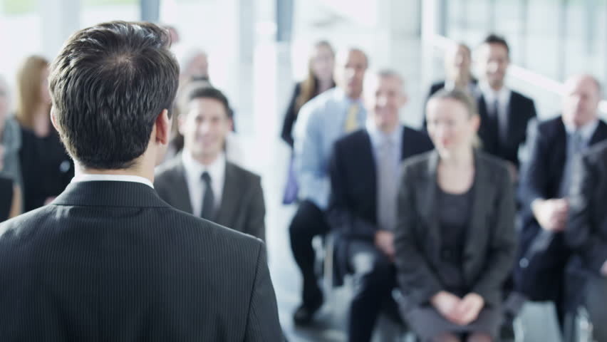 A diverse group of business people of mixed ages are listening to a presentation at a business seminar and asking questions. In slow motion. 