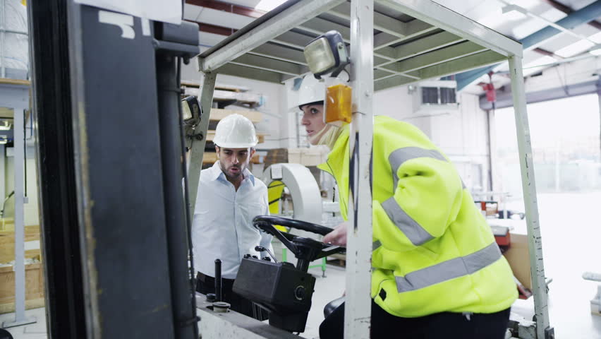 A male forklift truck driver arrives on shift in a factory or warehouse to take over from his female co-worker. In slow motion.