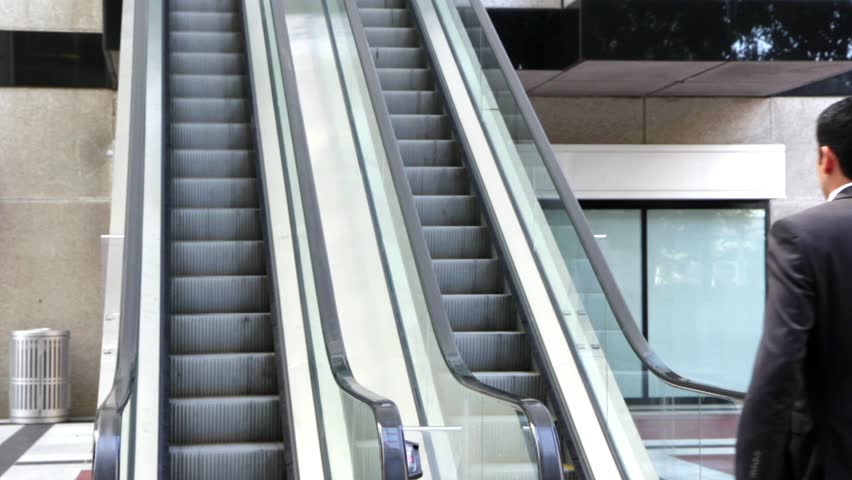 Confident businessman walking to an escalator 
