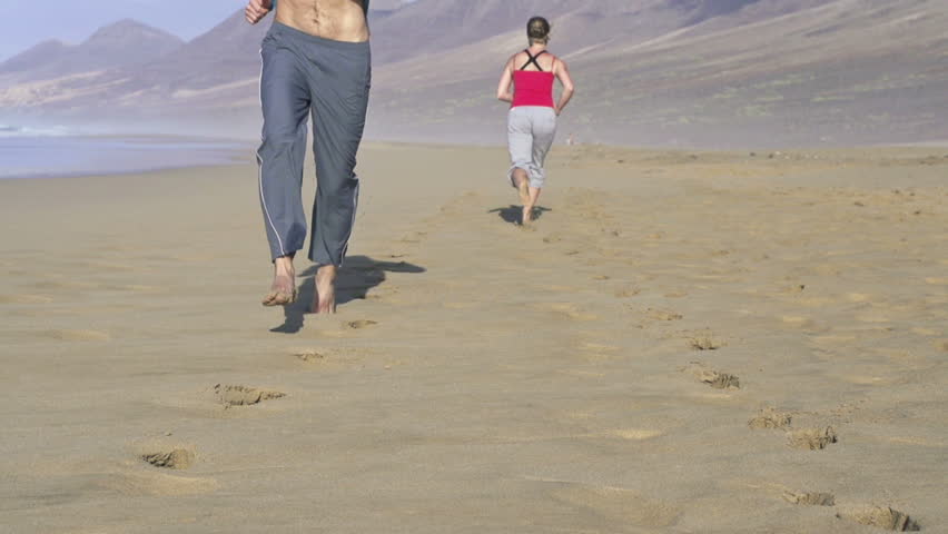 Man and woman jogging on the beach, super slow motion, shot at 240fps
