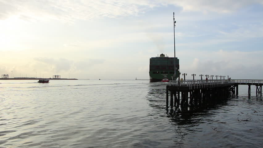 Los Angeles, CA - CIRCA May 2013: Container Ship Xin Hong Kong IMO: 9314222 departing the Port of Los Angeles at sunrise with Pilot Boat approaching dock.