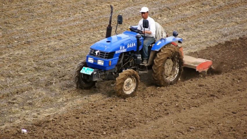 HEILONGJIANG PROVINCE, CHINA - CIRCA MAY 2013: Tractor plowing the field (07). Chinese farmer on a small tractor plowing a field in spring day. Medium shot, tracking focus. North China, Heilongjiang Province, May 2013.