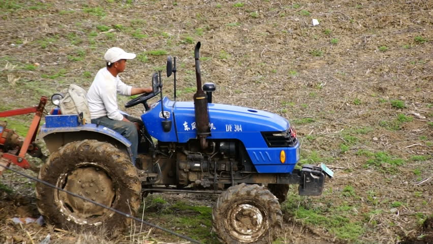 HEILONGJIANG PROVINCE, CHINA - CIRCA MAY 2013: Tractor plowing the field (09). Chinese farmer on a small tractor plowing a field in spring day. Close up, tracking focus. North China, Heilongjiang Province, May 2013.
