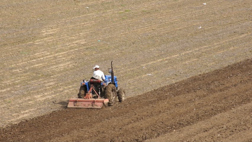 HEILONGJIANG PROVINCE, CHINA - CIRCA MAY 2013: Tractor plowing the field (09). Chinese farmer on a small tractor plowing a field in spring day. Long static shot. North China, Heilongjiang Province, May 2013.