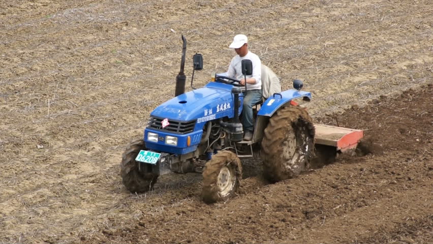 HEILONGJIANG PROVINCE, CHINA - CIRCA MAY 2013: 
Tractor plowing the field (02). Chinese farmer on a small tractor plowing a field in spring day. Static, medium shot. North China, Heilongjiang Province, May 2013.
