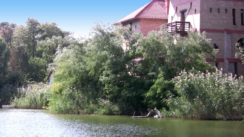 Small pond. Fortress in the old style on the banks of the pond. Reeds on the banks of the pond ripples from the wind. Cloud creeps on the blue sky and hide the sun