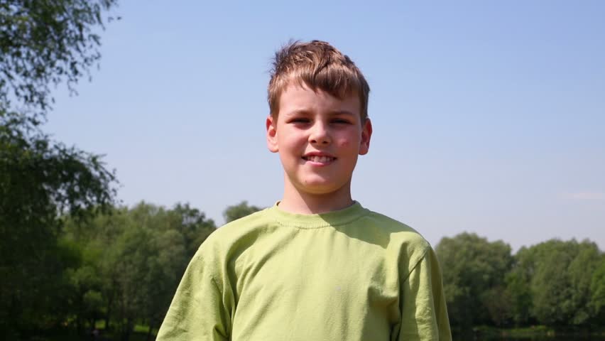 Boy in green t-shirt raises picture frame and his head passes through it