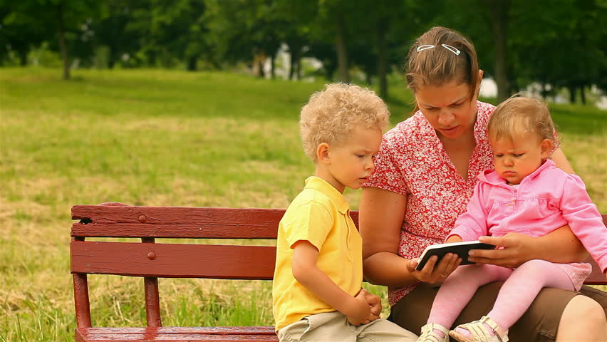 mother and two children, reading and watching Tablet Computers