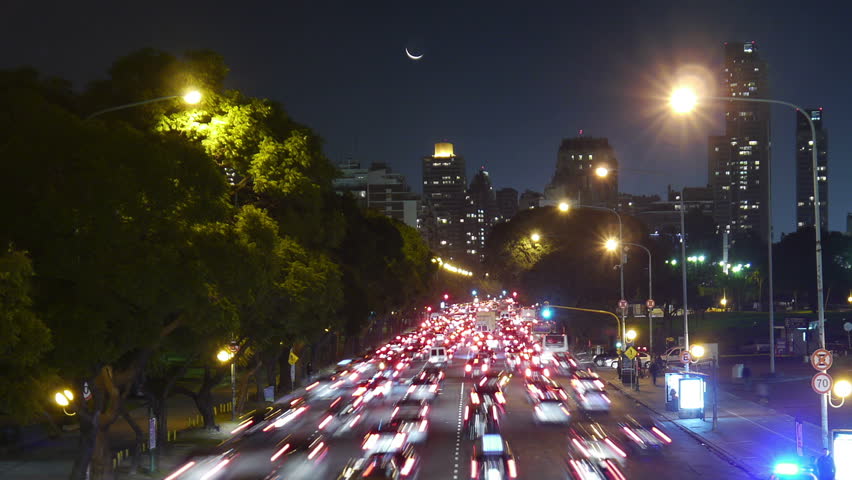 Traffic in the city. Avenue Time-Lapse, Night. Moon going down. Heavy traffic / jam / flowing with blurred motion. Dusk. Crane motion.