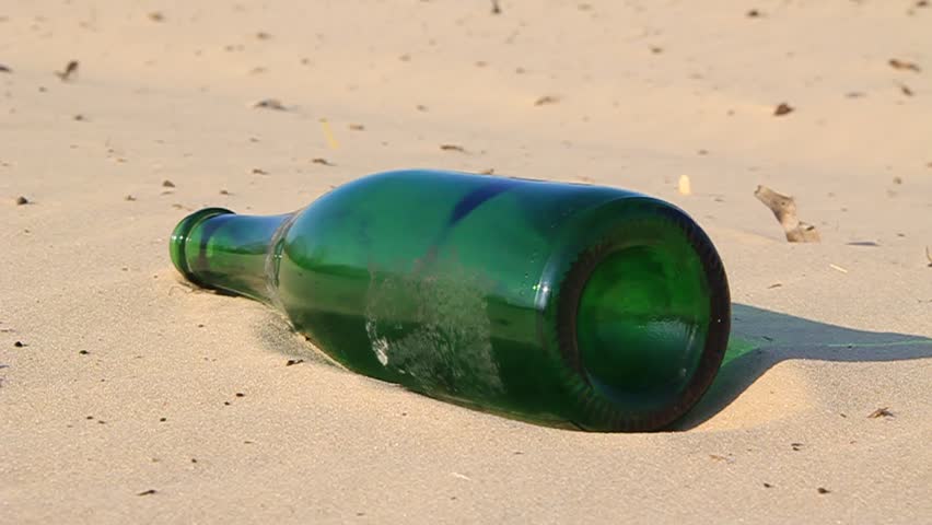 Green bottle on the sand