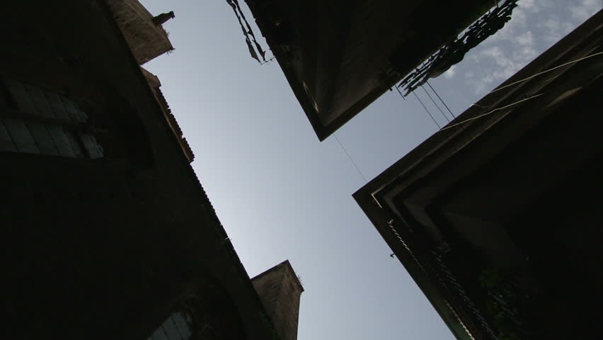 Sky chink. Gap with cloudscape between houses and laundry in the wind in Gothic quarter in Barcelona. Spinning. Loop ready.