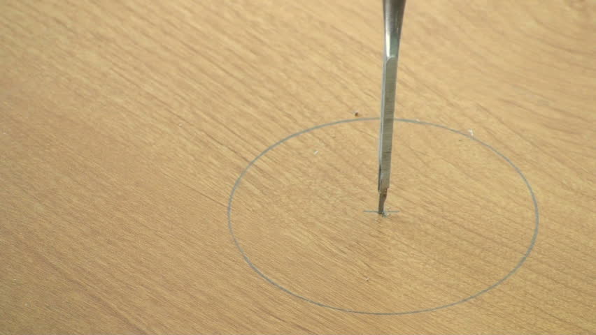 Carpenter uses flat bit to drill hole in finished wooden desktop to allow computer wire access.