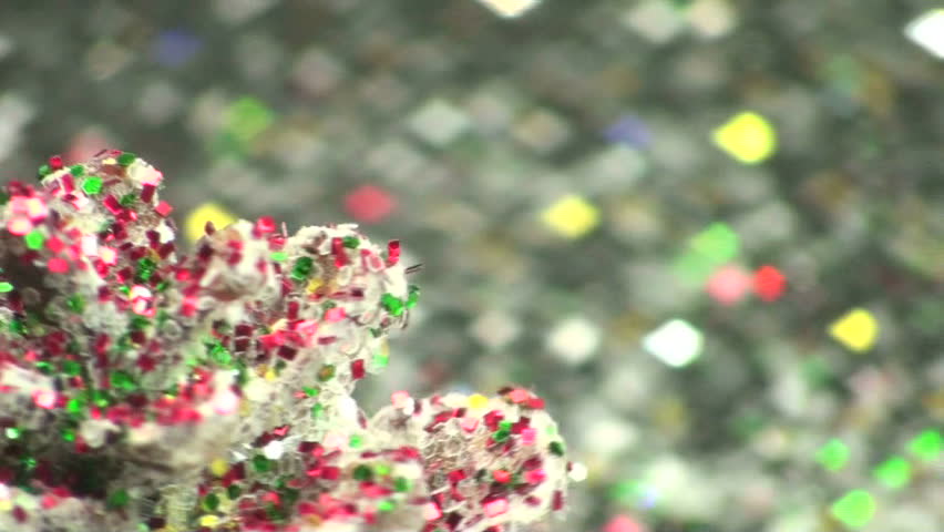 Glitter-covered cone twirls around background glistening with multi- colored crystals.