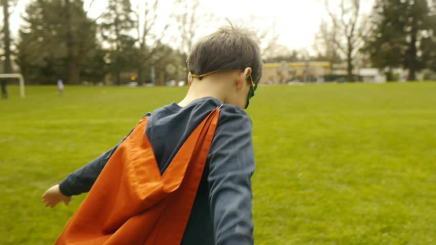 Superhero Boy Runs Around Park Pretending To Fly