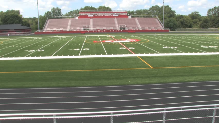 Moving along a football field and empty bleachers. Shot with a stabilizing Glidecam. 