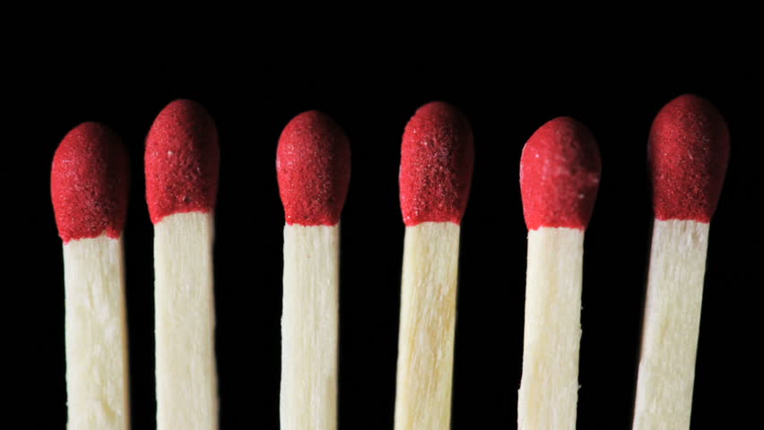 A close up of six match at the point of ignition on a black background.