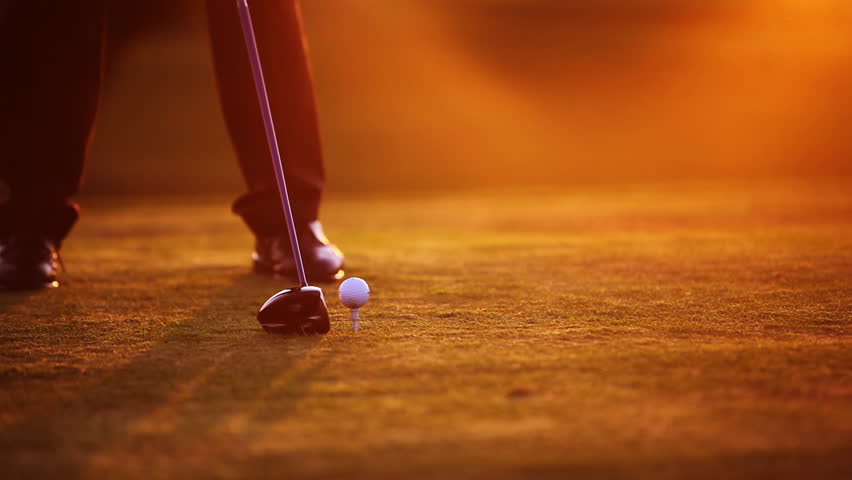 Golf player teeing off on beautiful golf course during dawn