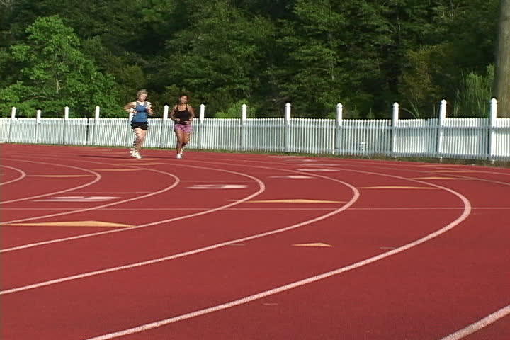 Two coeds jog on the university track to burn calories and loose weight.
