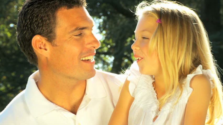 Young father tenderly holding his daughter while outdoors on a summers day