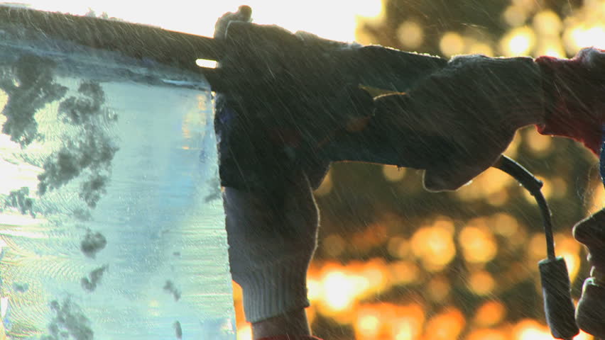 Ice carving 1- Ice carver using a chain saw on some ice at sunset outdoor display