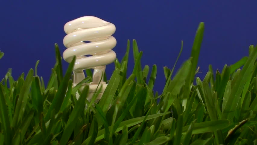 Energy saving light-bulb in grass against blue background