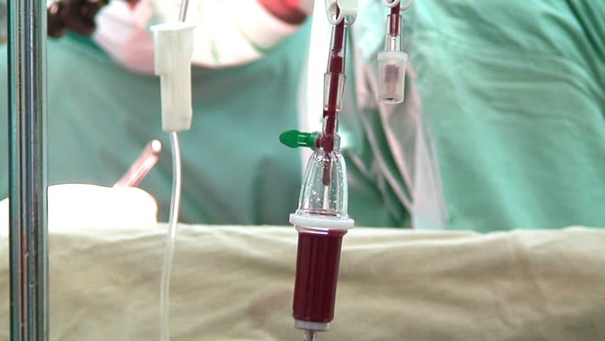 blood drip in operation room with surgeons on background 