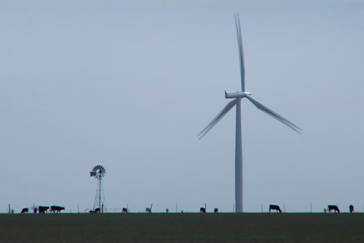 An old-fashioned windmill stands next to a towering wind turbine - old and new, side by side.