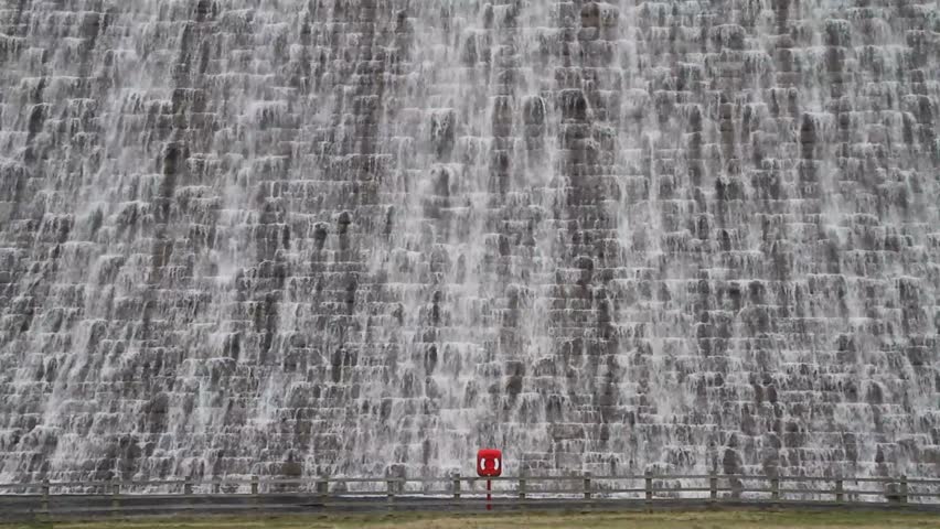 Water cascading over Derwent Water Dam with a single red life buoy in the foreground