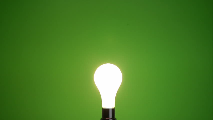 Hand replaces a dead incandescent bulb with a compact fluorescent, green background