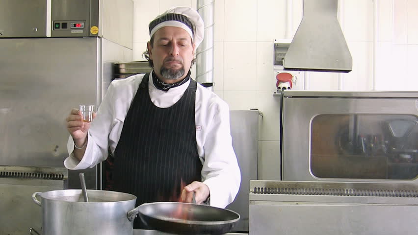 Mature chef holding pan and doing a flambe. Front view